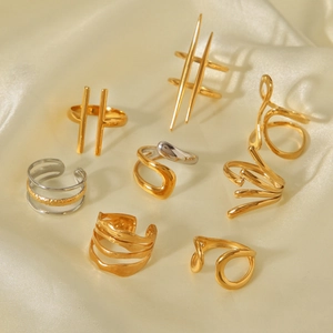 Detail of minimalist gold and silver irregular geometric rings on beige silk fabric