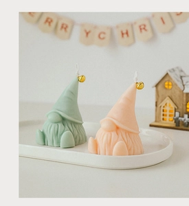 Detail of green and pink gnome scented candles with golden bells for Christmas decor