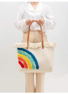 Dettaglio della borsa tote intrecciata beige con motivo arcobaleno e frange