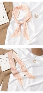 Detailed view of pink floral silk scarf with letter prints styled on soft fabric