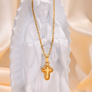 Detailed close-up of golden cross pendant with dot texture on elegant white statue