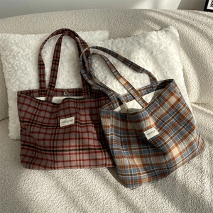 Detail of vintage plaid wool tote bags with textured fabric and stitched logo label