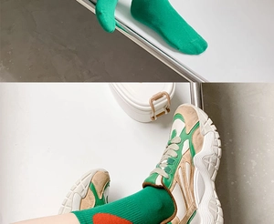 Detail of green mid-calf socks with red heart motif worn with vintage suede sneakers