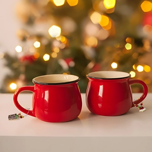 Red ceramic mugs with festive Christmas wine glass charms on a holiday table setup