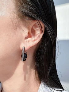 Detailed view of silver bar earring with a black onyx sphere bead on a model's ear