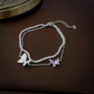 Detail of double-layer butterfly bracelet with purple zircon and shell charm on leather