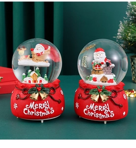 Close-up of Santa Claus snow globe with a red Merry Christmas gift bag base