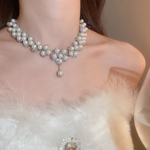 Elegant necklace set with sparkling floral pearls worn by a model on a white feather top