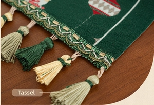 Detailed macro view of dark green Christmas table runner with festive tassels and knit texture