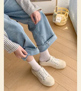 Detailed shot of cream low-cut cotton socks with vertical stripes and canvas shoes