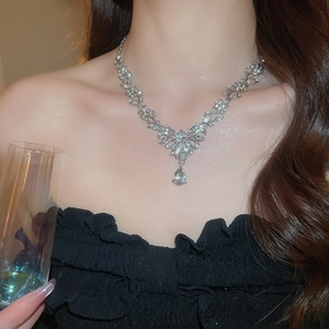 Detailed view of elegant silver floral necklace with sparkling teardrop pendant on model
