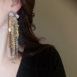 Detailed macro of crystal stud earrings with cascading gold and silver fringe chains