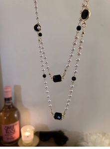 Detail of layered pearl necklace with black gems and gold hardware in elegant setting