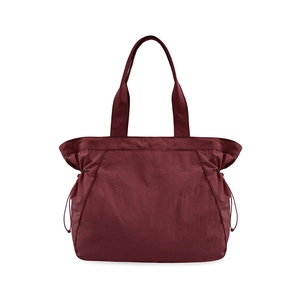 Detail of wine red nylon tote bag featuring adjustable side drawstrings and smooth texture