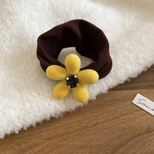 Détail d'un chouchou avec fleur en velours, tissu café et pétales jaunes avec pierre noire