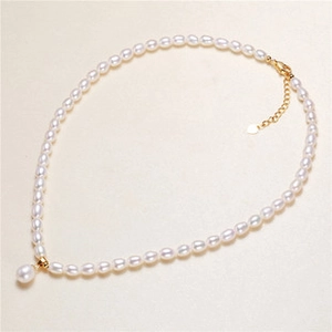 Detail of cream pearl necklace with gold-plated clasp and heart-shaped pendant