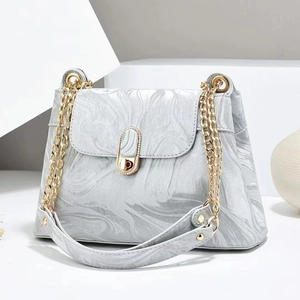 Detail of grey marble textured handbag featuring gold chain and oval twist lock