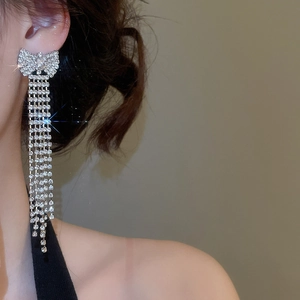 Close-up of elegant bow rhinestone tassel earrings worn on model for a luxury look