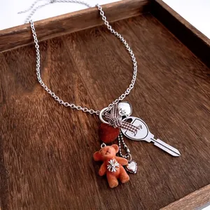 Flocked bear and heart pendant chain necklace with lucky key on a wooden display