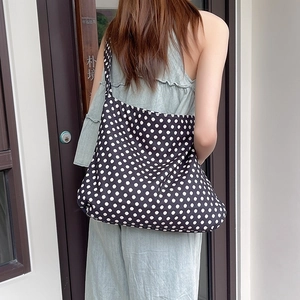 Detailed view of canvas shoulder bag featuring classic black and white polka dot patterns