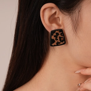 Close-up of leopard print trapezoid stud earrings with faux leather texture on model