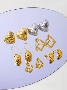 Assorted gold and silver textured heart earrings and hoops on a lavender mirror tray