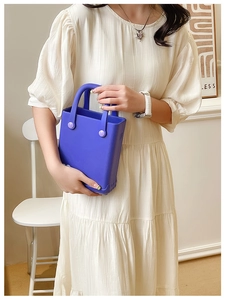 Detail einer mini hellblauen EVA-Gelee-Handtasche, von einem Model in Wohnumgebung gehalten