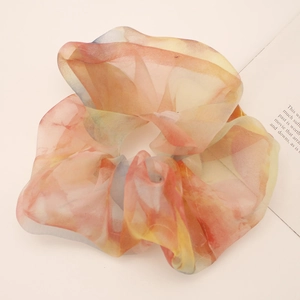 Detail shot of a large organza scrunchie with soft pastel orange and blue gradient colors