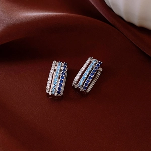 Detail of square silver hoop earrings with triple row blue and white zircon inlay