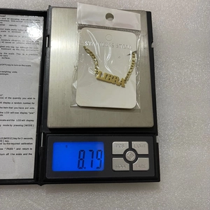 Detailed view of an 18K gold stainless steel Libra necklace weighing 8.79g on a digital scale