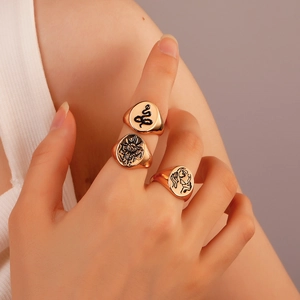 Detail of vintage gold signet ring set featuring snake and sun motifs on model fingers