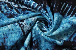 Macro detail of the blue and black abstract patterned fabric with silky texture on the dress