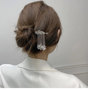 Detailed back view of a silver cloud hair pin with flowing tassels on a brown updo