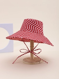 Detail of red polka dot sun hat with wide brim and matching chin strap for beach