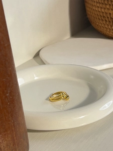 Macro shot of gold layered circular rings on a white ceramic tray with minimalist design