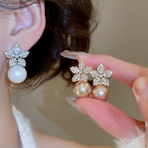 Macro detail of elegant flower pearl earrings with sparkling crystals in gold and silver