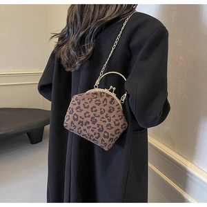 Chic leopard print clasp bag with gold chain strap worn over a black winter coat