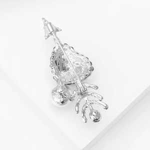 Close-up of a silver heart-shaped brooch with arrow design and pearl accents