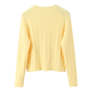 Pale yellow cable knit long sleeve sweater with ribbed cuffs on white background