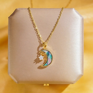 Collier lune et étoile doré avec incrustation irisée sur un coffret à bijoux de luxe