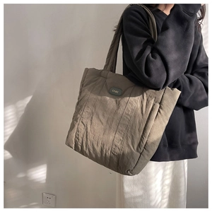 Quilted olive brown nylon puffer tote bag with EARE brand label shown in use