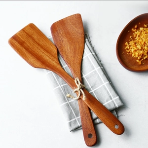 Close-up of natural wood spatulas with grain texture on grey checkered cloth napkin