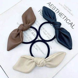 Three bow-knot elastic hair ties in brown, dark blue and beige made of PU leather material