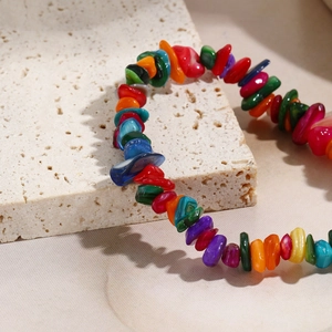 Macro detail of colorful irregular stone beads and shells on a textured stone stand