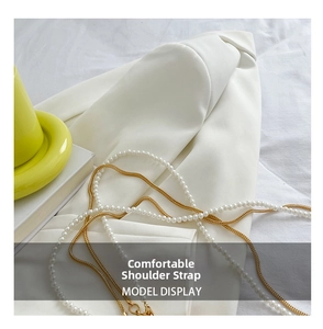 Detail of elegant pearl and gold metal chain strap on a white blazer background