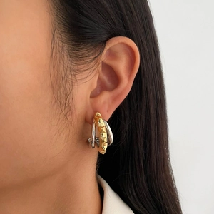 Modern gold and silver layered stud earrings with spike accents on female model