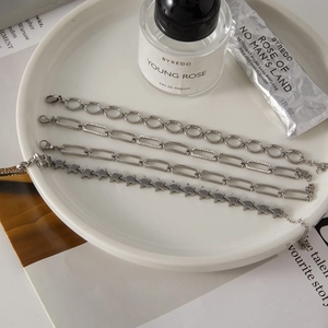 Close-up of four silver stainless steel bracelets with stars and link details on a tray