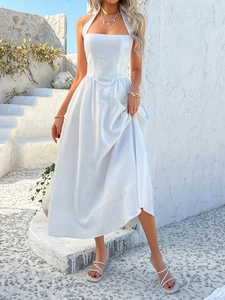 Close-up of a white halter neck maxi dress with pleated fabric in a resort setting