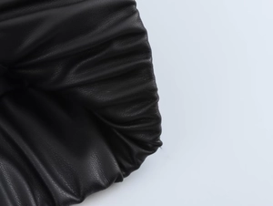 Dettaglio ravvicinato della giacca in pelle nera con texture plissettata e cuciture fini