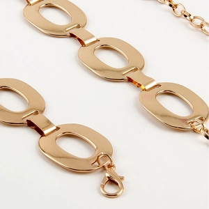 Detail of a stylish gold metal waist chain belt with oval links and a lobster clasp closure